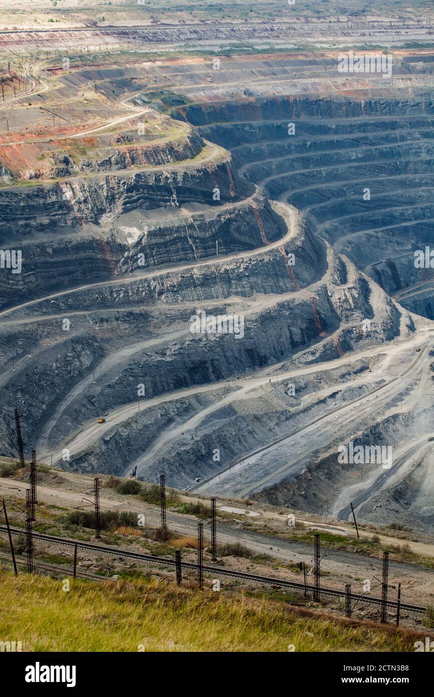Cava di minerale di ferro gigante a Rudny, Kazakhstan. Minerali grezzi minerari a cielo aperto per la produzione di acciaio. Ferrovia in primo piano. Foto Stock