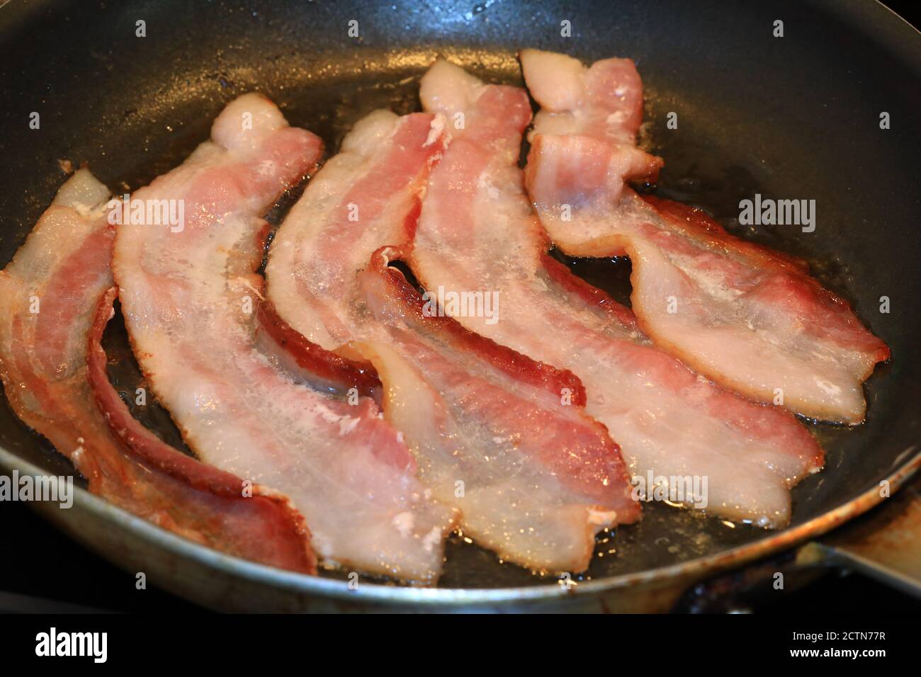 Pancetta cruda in cottura Foto Stock