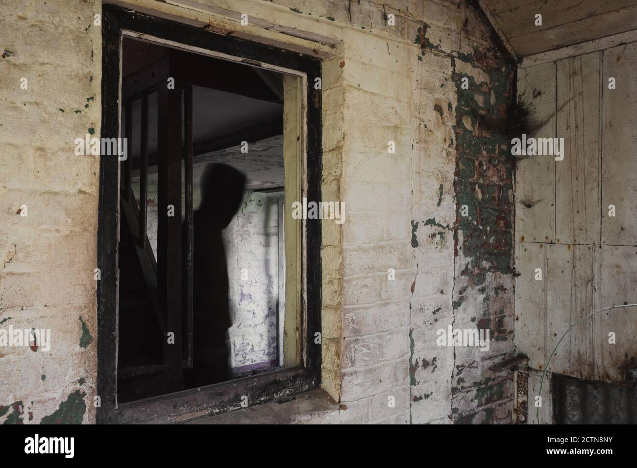Una figura sfocata e spettrale. Incorniciato in una finestra in una decadente vecchia casa abbandonata Foto Stock