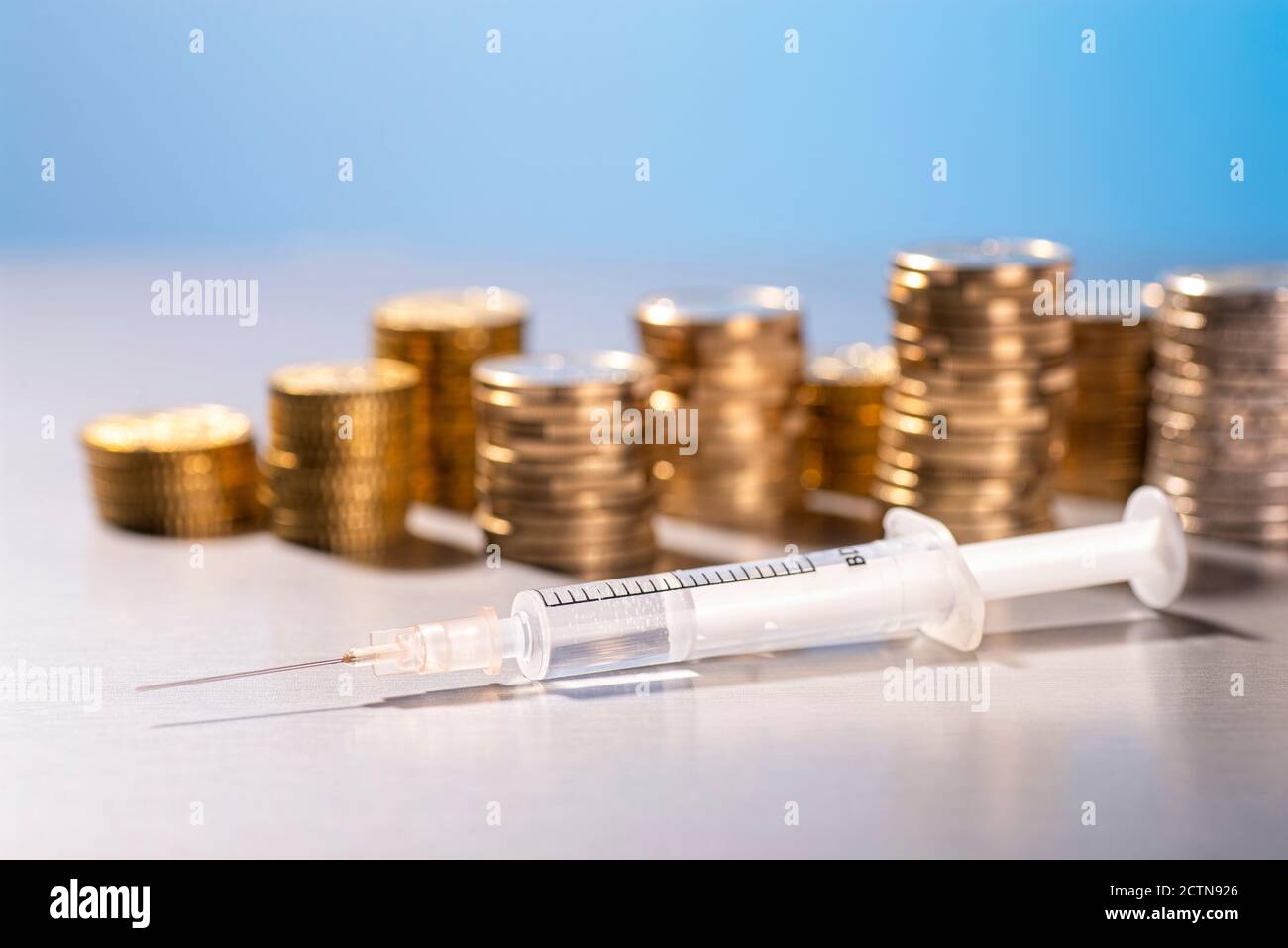 Siringa con vaccino prima di impilare le monete Foto Stock
