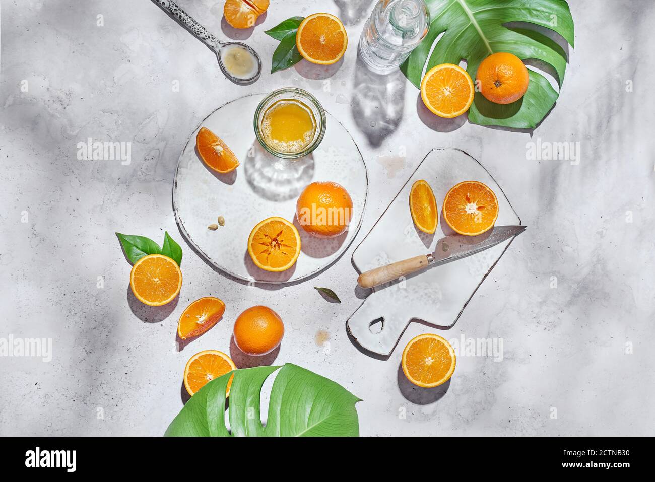 Vista dall'alto di arance intere e metà mature disposte sul tavolo con coltello e bicchiere con succo Foto Stock