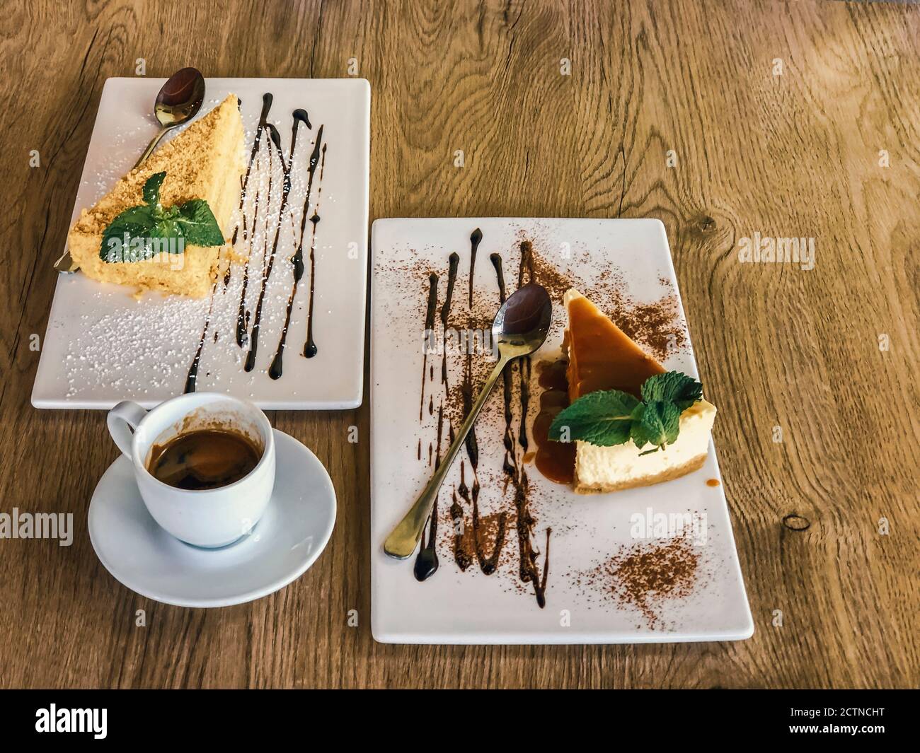 due fette di napoleone e torta al formaggio su piastra di terracotta bianca con fondo in legno. primo piano foto con fuoco selettivo. Foto Stock