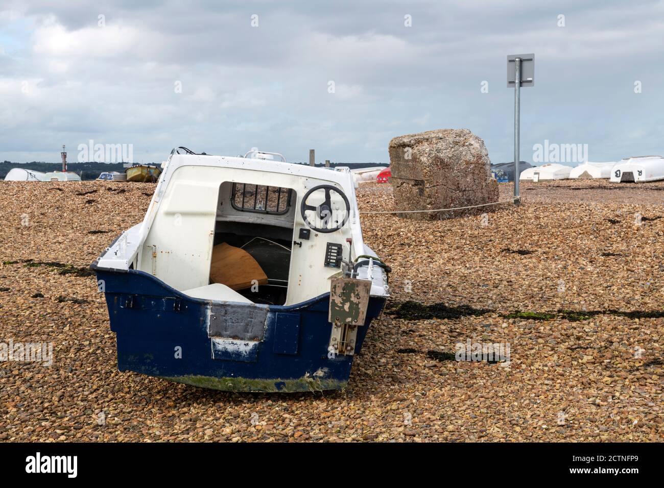 Piccolo motoscafo spiaggiato sulla riva dello shingle, porto di Langstone Foto Stock