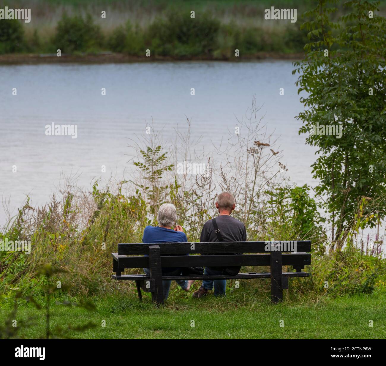 Maashees, Olanda, 09-set-2020: Coppia più anziana siedono su una panchina che guarda fuori river mesh e pensare alla vita Foto Stock