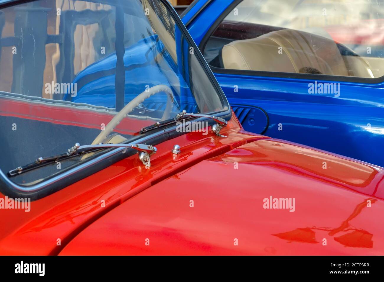 Cofano e parabrezza di un'auto rossa sullo sfondo di un primo piano di un'auto blu. Foto Stock