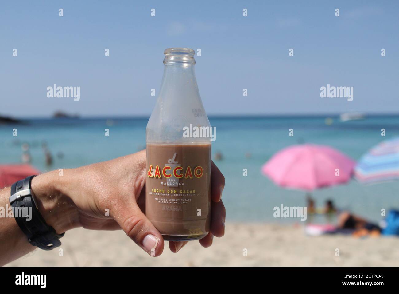 Un turista ama un po' di tempo sulla spiaggia di Cala Torta, Maiorca (Spagna) bevendo un frullato di cioccolato. / Ana Bornay Foto Stock