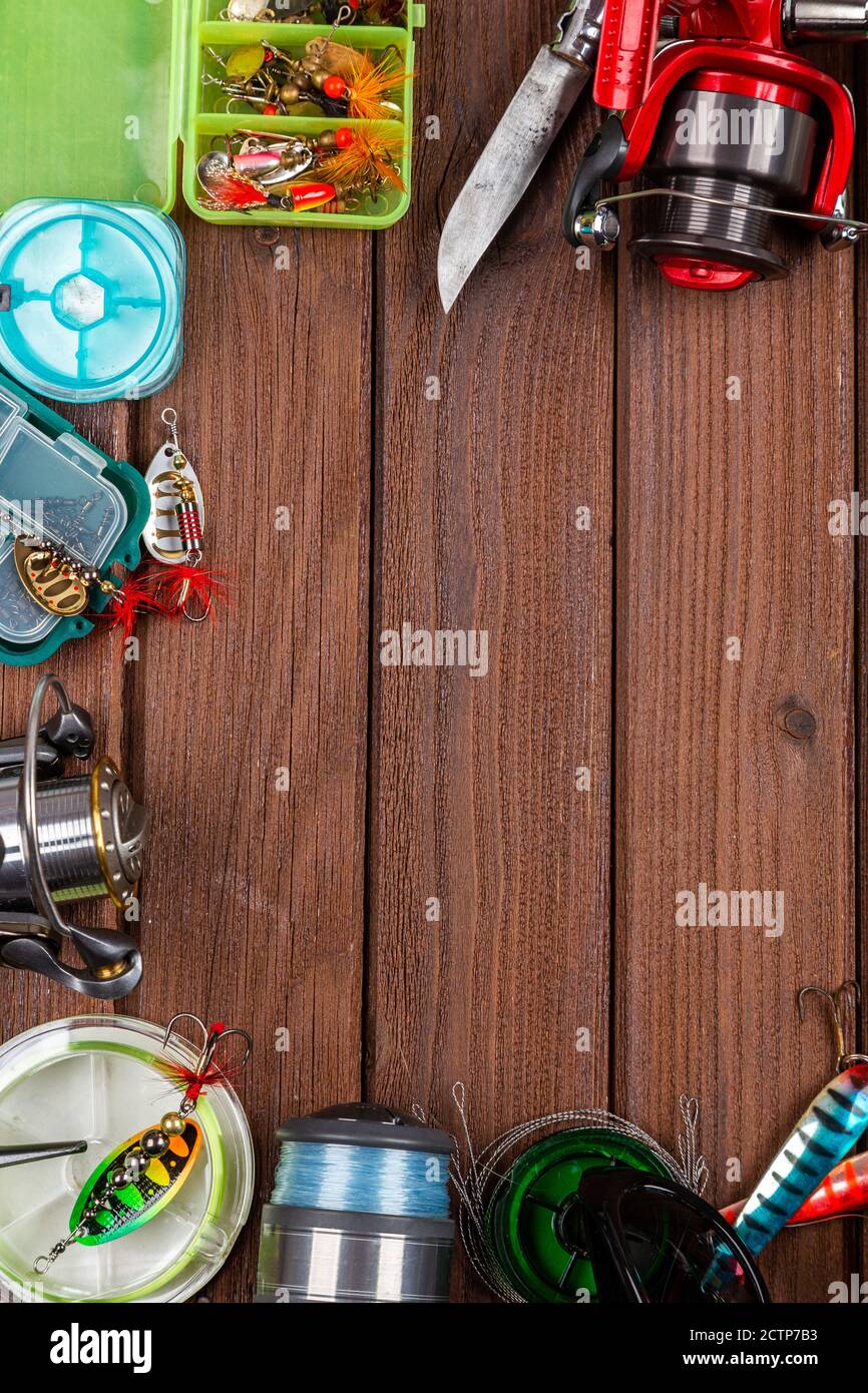 Diverse tegole da pesca con esche e bobine su sfondo marrone di legno con posto per il testo. Design per la pubblicità e la pubblicazione. Foto Stock