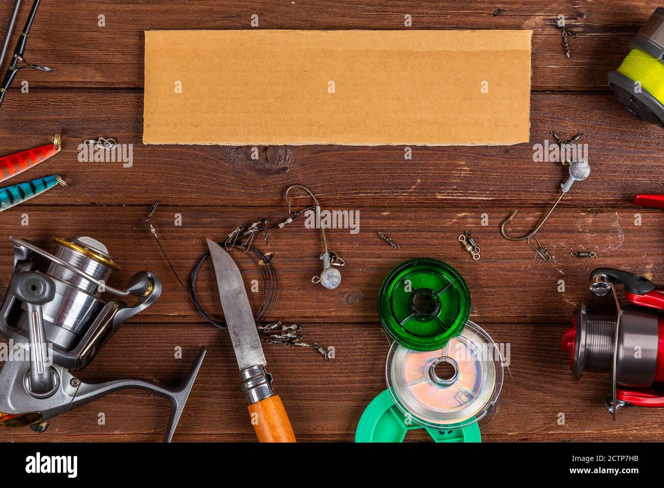 Diverse tegole da pesca con esche e bobine su sfondo marrone di legno con posto per il testo. Design per la pubblicità e la pubblicazione. Foto Stock