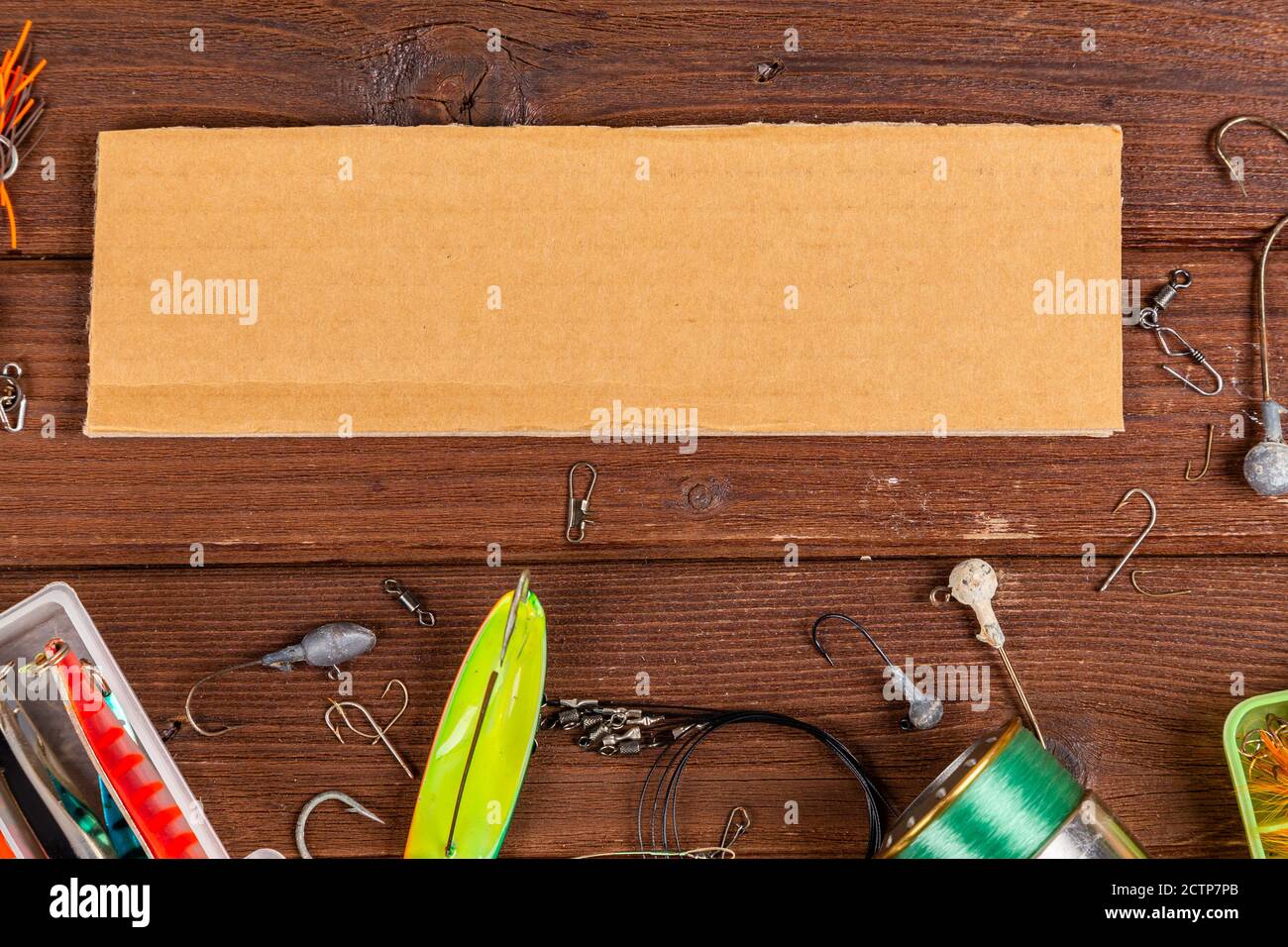Diverse tegole da pesca con esche e bobine su sfondo marrone di legno con posto per il testo. Design per la pubblicità e la pubblicazione. Foto Stock