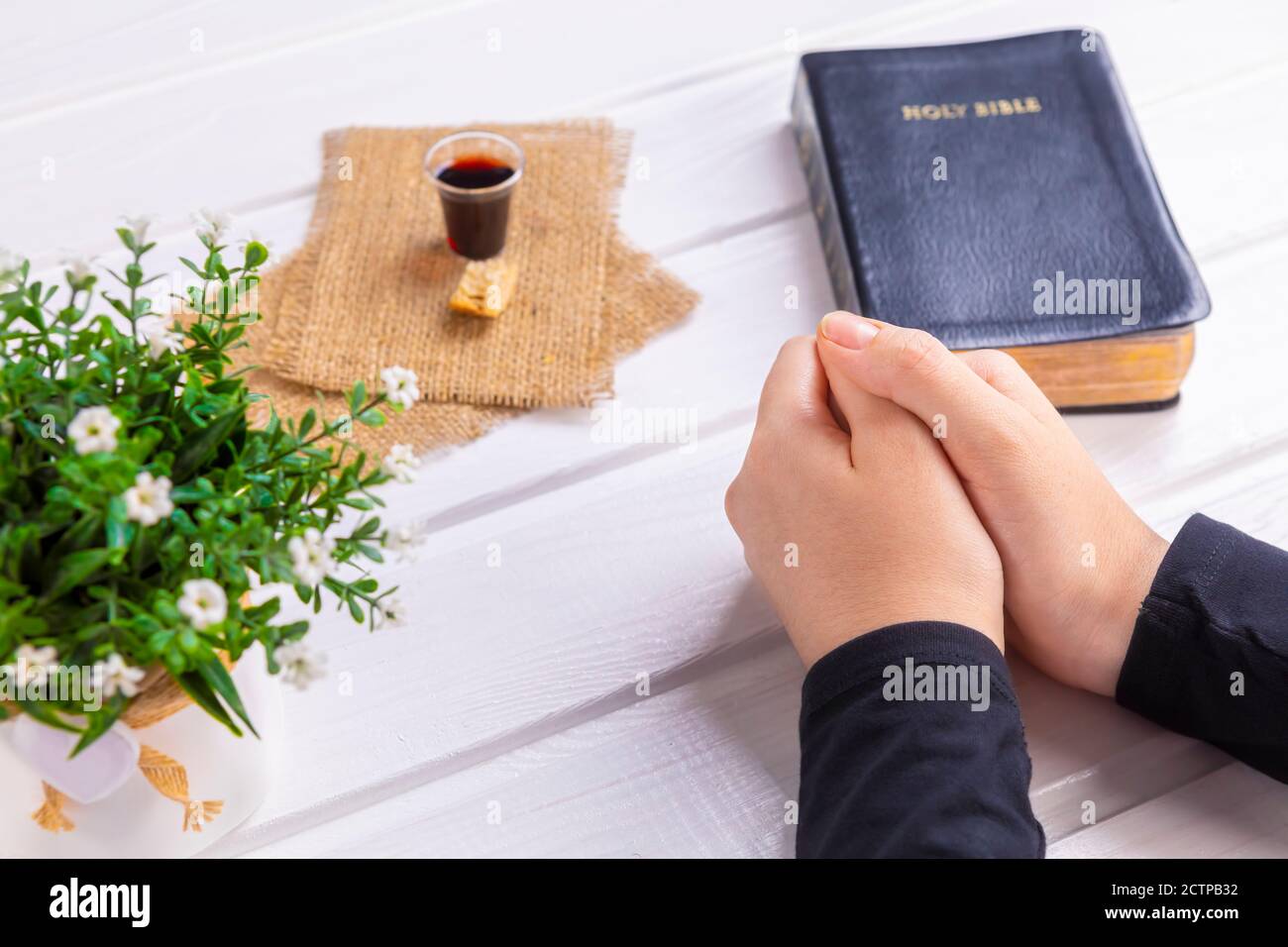 Giovane donna che prega e prende comunione - il vino e i simboli del pane di Gesù Cristo sangue e corpo con la Sacra Bibbia. Pasqua Pasqua Pasqua e Signore su Foto Stock