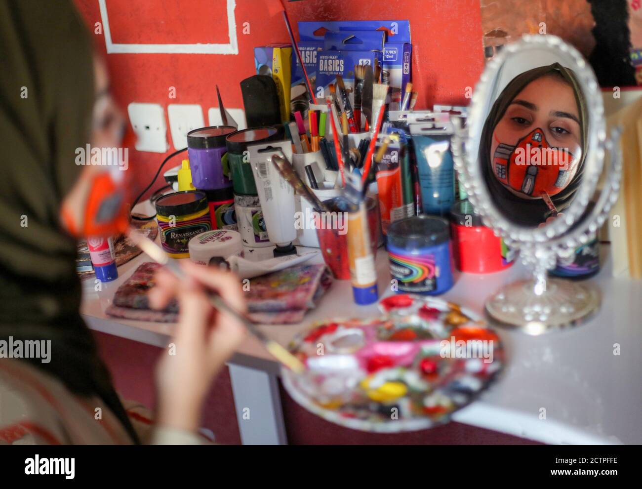 Gaza, Palestina. 23 Settembre 2020. La ragazza palestinese guarda attraverso lo specchio mentre dipinge una maschera sul suo viso.Nineteen-year-old Ranin al Zeriei dipinge maschera sul suo volto nella città di Deir al Balah striscia di Gaza meridionale in mezzo al coronavirus in corso COVID-19 pandemia. Credit: SOPA Images Limited/Alamy Live News Foto Stock