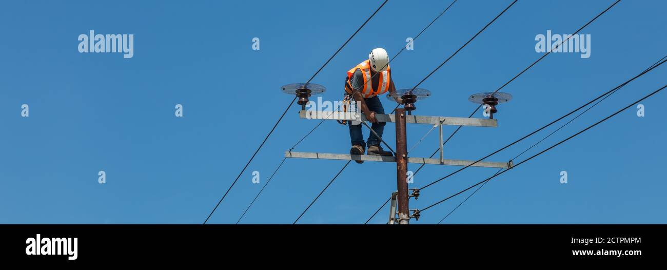 Tenhilan, Sabah, Malesia: Un uomo di linea non protetto sta salendo sulla cima di un pilone ad alta tensione a Tengilan, incline a una caduta pericolosa. Foto Stock