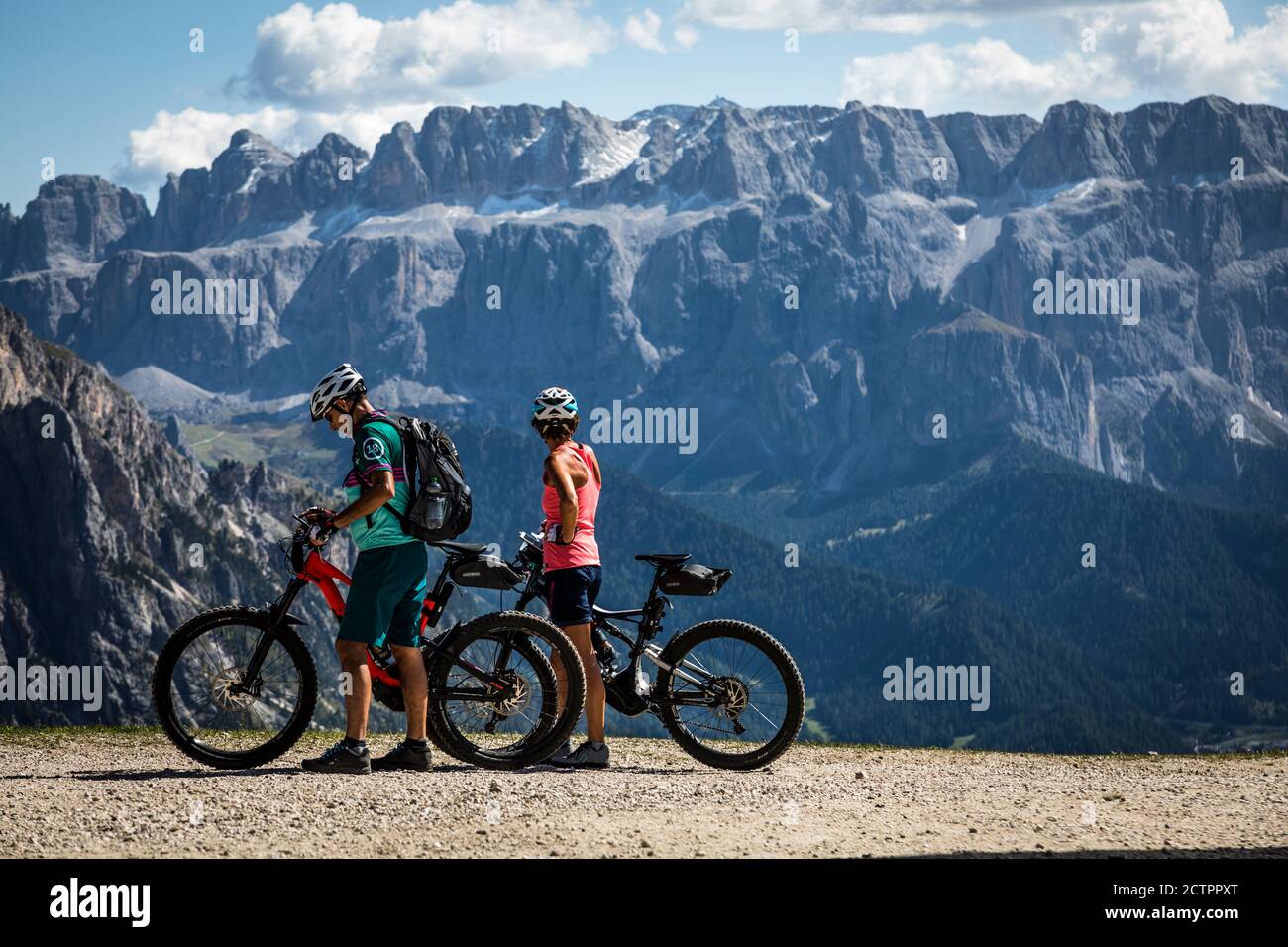 Due ciclisti con mountain bike ammirano la vista del Massiccio del Sella fuori dalla stazione della funivia Seceda , Val Gardena, Italia. Foto Stock