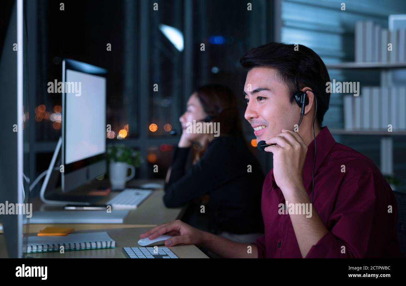 Giovani Thai Asian servizio clienti operatori di assistenza che lavorano turno di notte in call center per aiutare il cliente di assistenza sul posto di lavoro in notte Foto Stock
