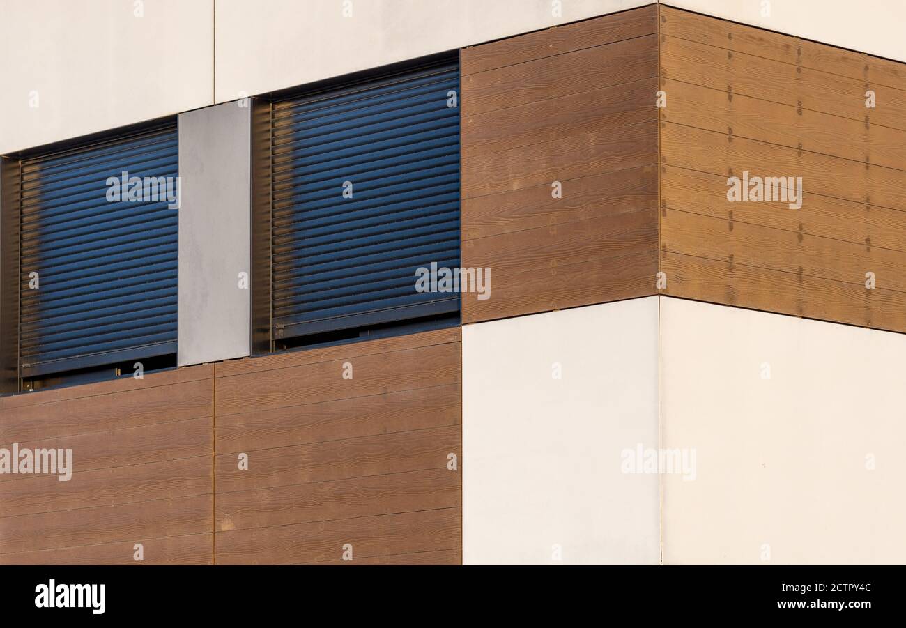 Facciata di una casa moderna con tavole di legno e finestre con persiane al tramonto Foto Stock