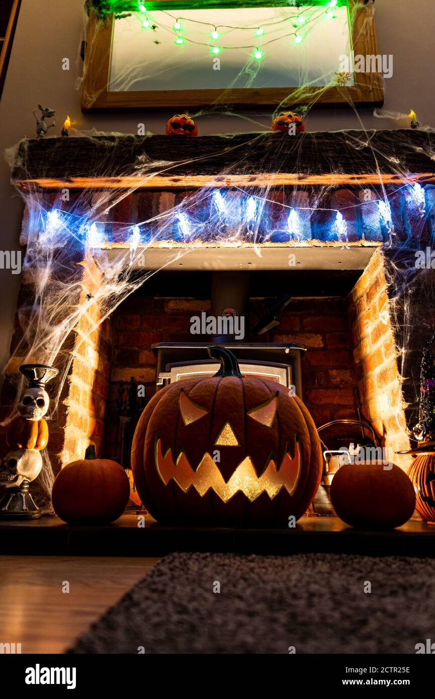 Grande zucca di Halloween sul camino davanti al fuoco. Luce blu sul viso Foto Stock
