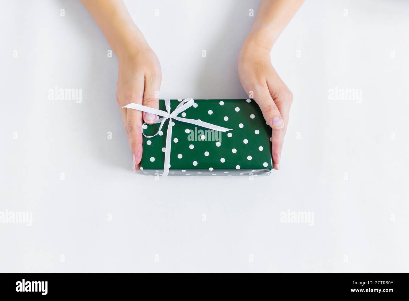 Le mani stanno tenendo un regalo in imballaggio verde. Foto Stock