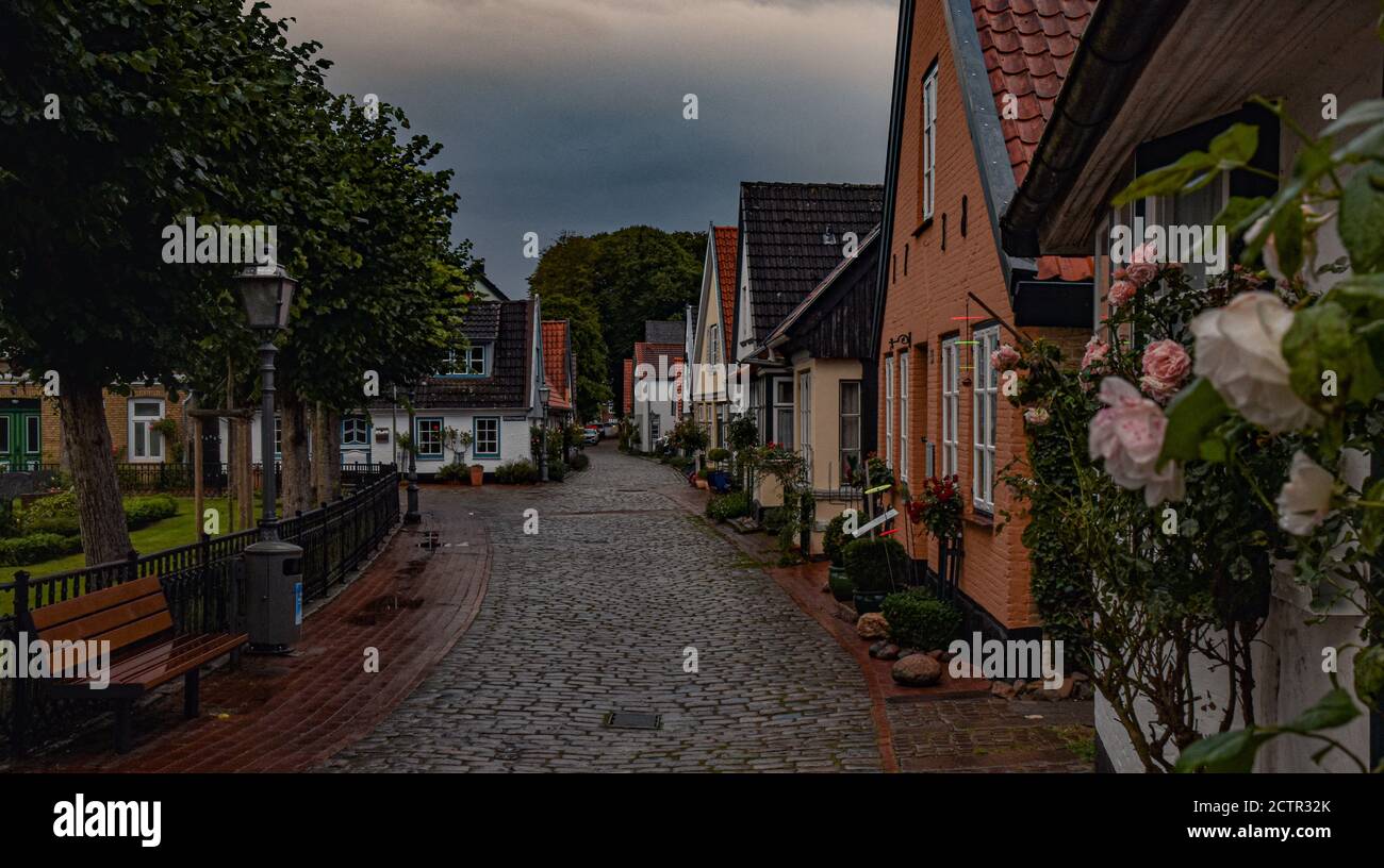 Camminando lungo un vicolo in un giorno tempestoso nel villaggio di pescatori di Holm in Schleswig, Germania Foto Stock