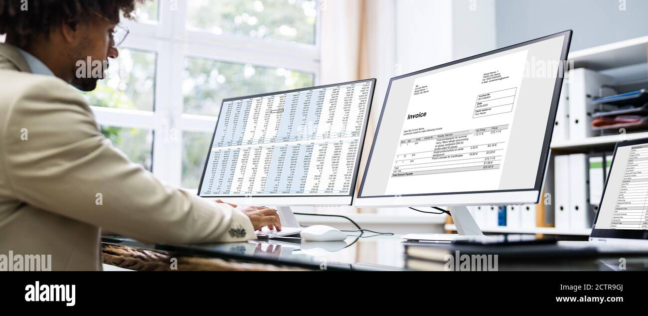Esame di fatture e fogli di calcolo sul computer al lavoro Foto Stock