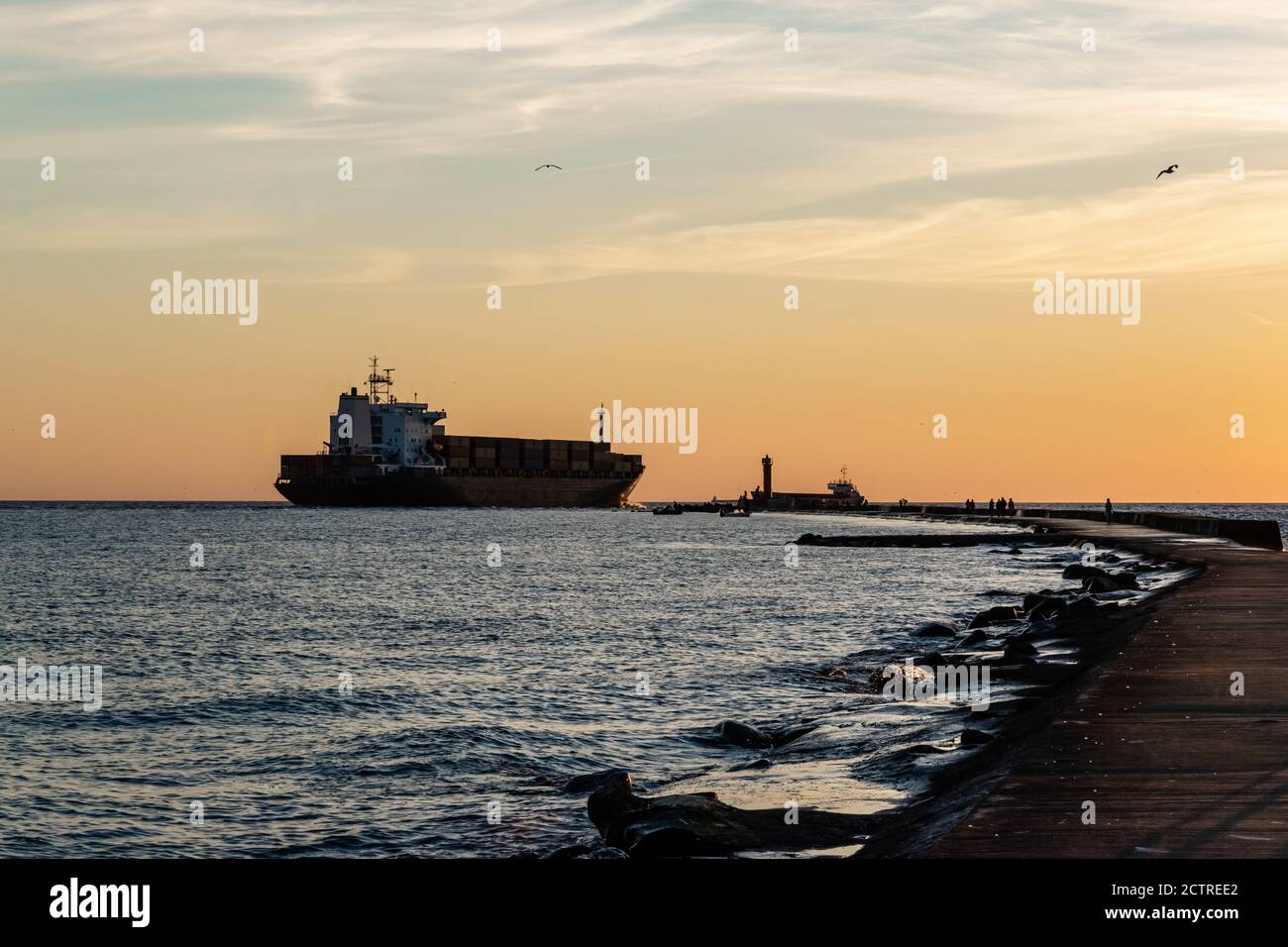 Spedizioni globali e attività commerciali in tutto il mondo. La nave portacontainer passa attraverso il faro per andare in mare aperto. Foto Stock