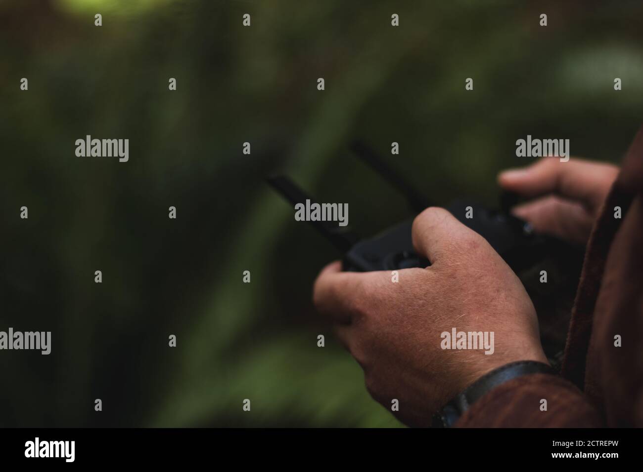 Primo piano di mans Hands che controlla il telecomando del drone visualizzando la messa a fuoco selettiva solo di una parte della mano mentre il telecomando è sfocato. Foto Stock