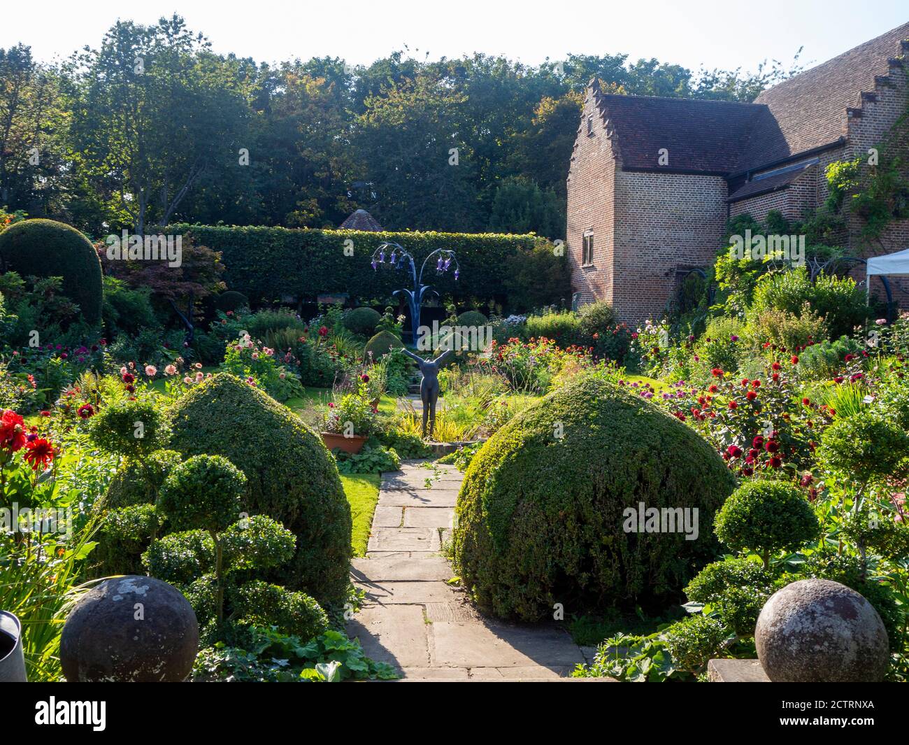 Chenies Manor House Sunken Garden su un soleggiato metà settembre pomeriggio, 2020. Variopinte varietà di dahlia in bordi di piante terrazzate, topiario, sculture. Foto Stock