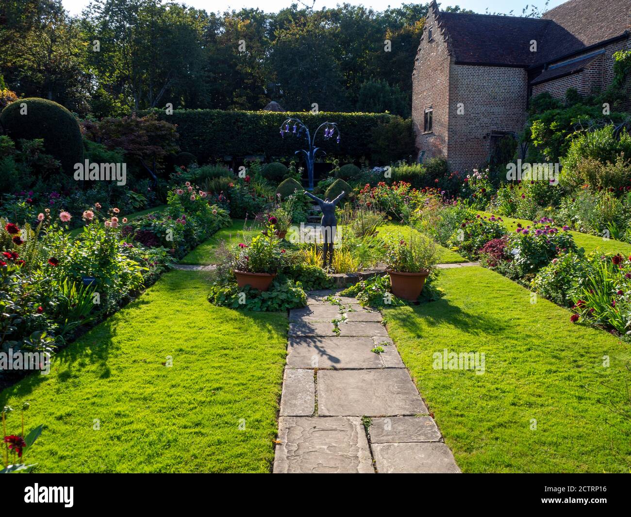 Chenies Manor House Sunken Garden in un pomeriggio soleggiato di settembre. Dahlias colorati in bordi erbacei delle piante, sculture e laghetto ornamentale. Foto Stock