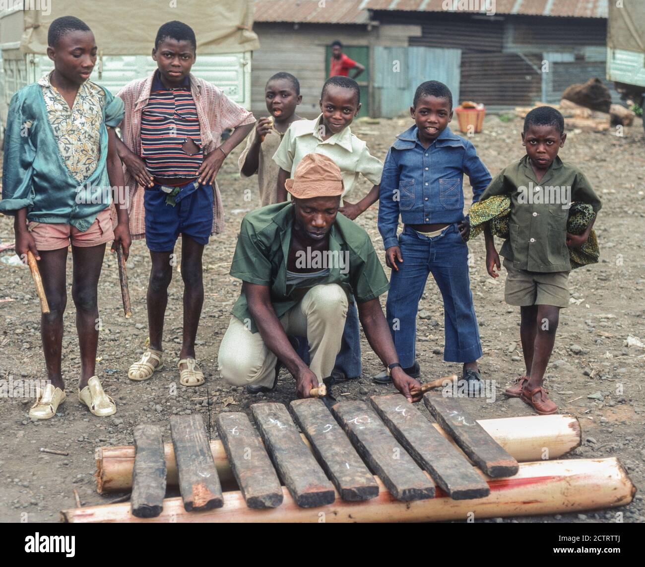 Buea, Camerun. Ragazzi giovani Guarda un giocatore Balafon che dimostra la sua abilità. Foto Stock