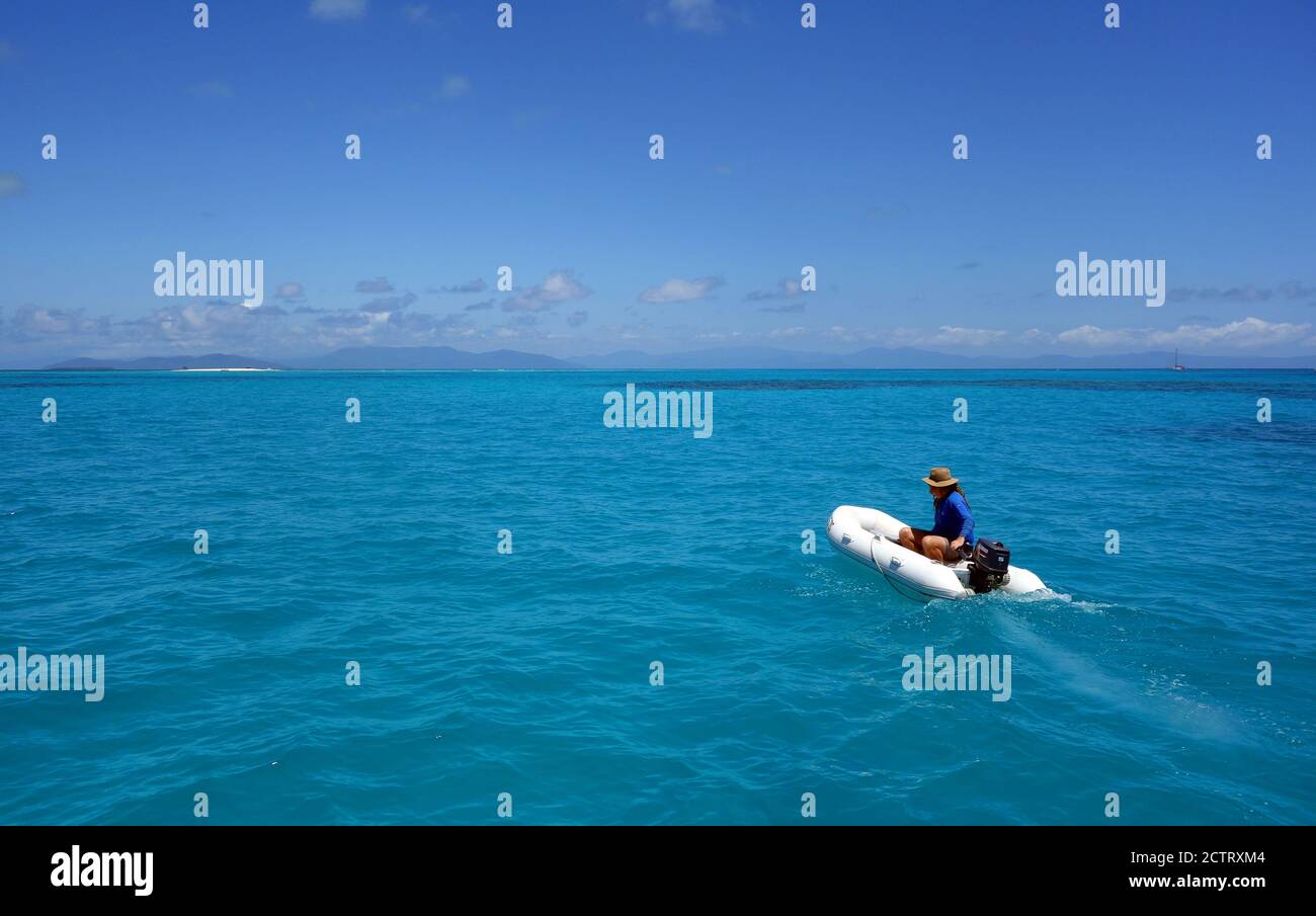 Uomo che guida dinghy a Vlassoff Cay, Grande barriera Corallina, Queensland, Australia. No MR o PR Foto Stock