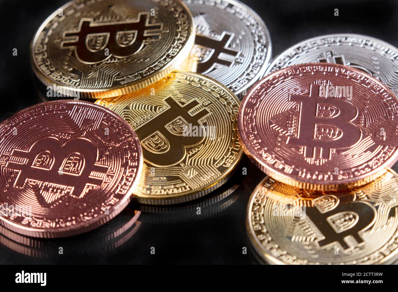 Primo piano di Bitcoins in oro, argento e rame su sfondo nero Foto Stock