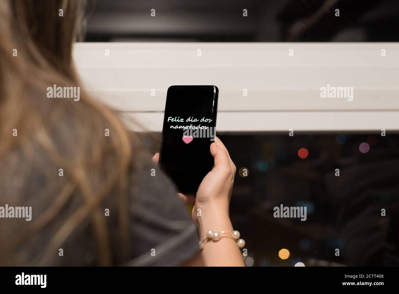 Donna brasiliana appeso un cellulare scritto 'Feliz dia dos Namorados' (Buon San Valentino in portoghese) Foto Stock