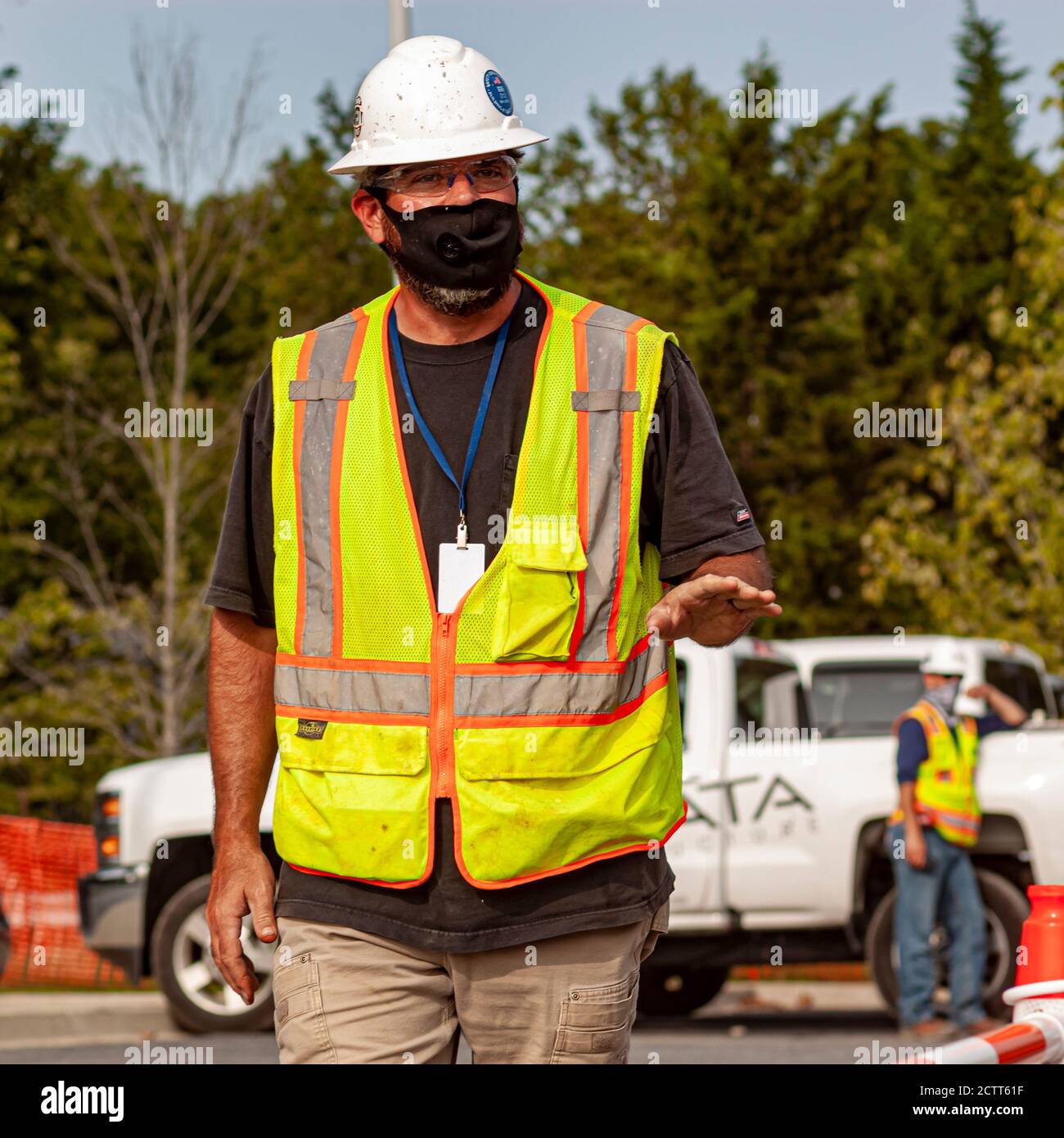 Bethesda, MD, USA 09/15/2020: Un operaio caucasico che indossa attrezzature di sicurezza come occhiali, casco e giubbotto riflettente sta camminando in const Foto Stock