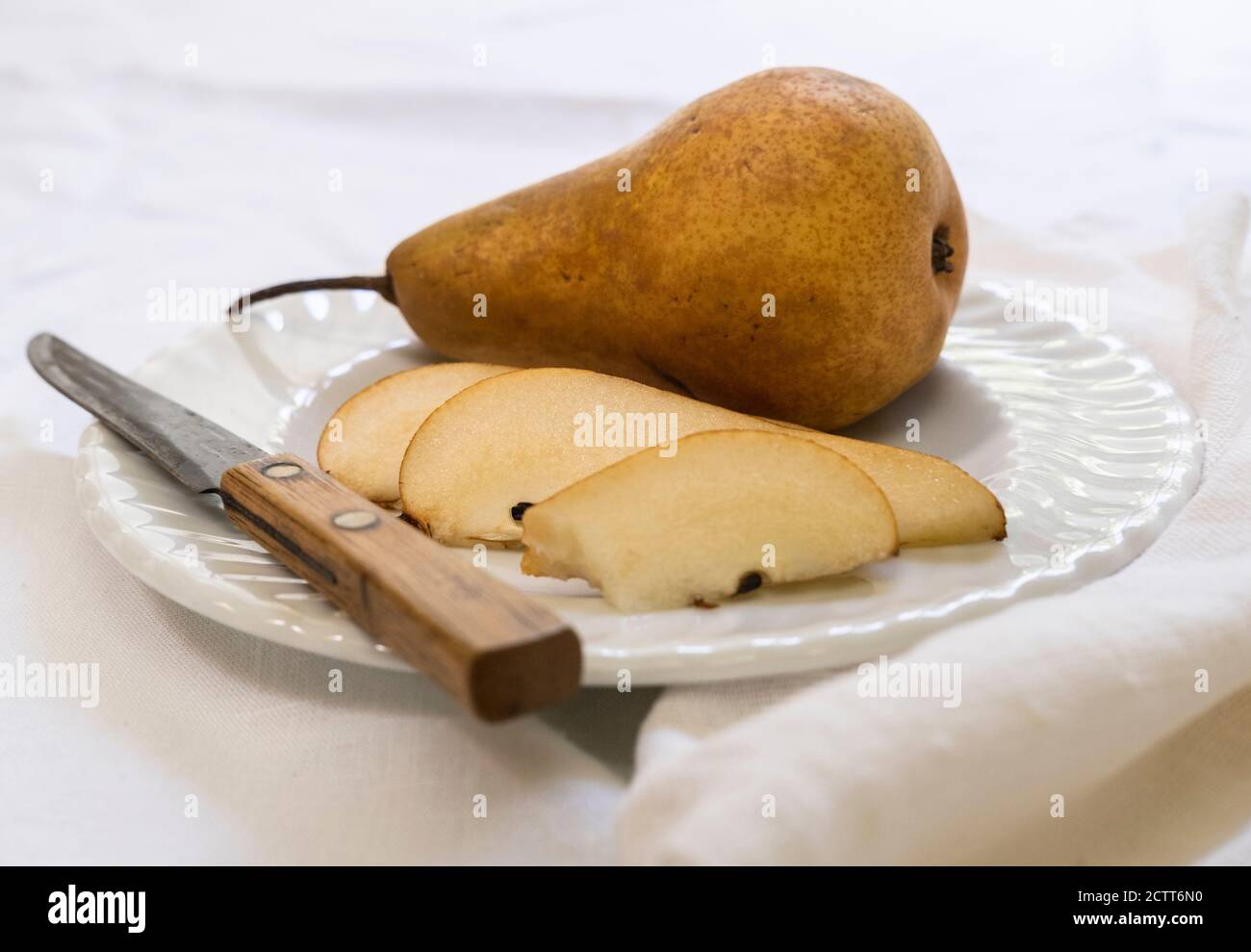 Pera e coltello a fette su piatto Foto Stock