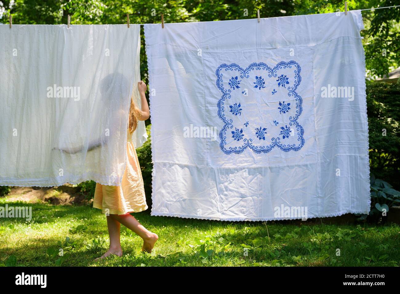 Ragazza (6-7) con lavanderia in cortile Foto Stock