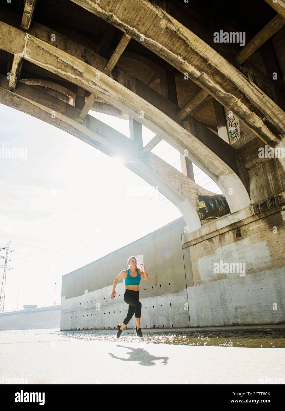 USA, California, Los Angeles, donna sportiva che corre sotto il ponte Foto Stock