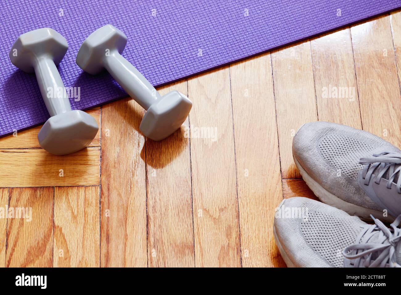 Pesi, tappetino yoga e scarpe da running sul pavimento Foto Stock