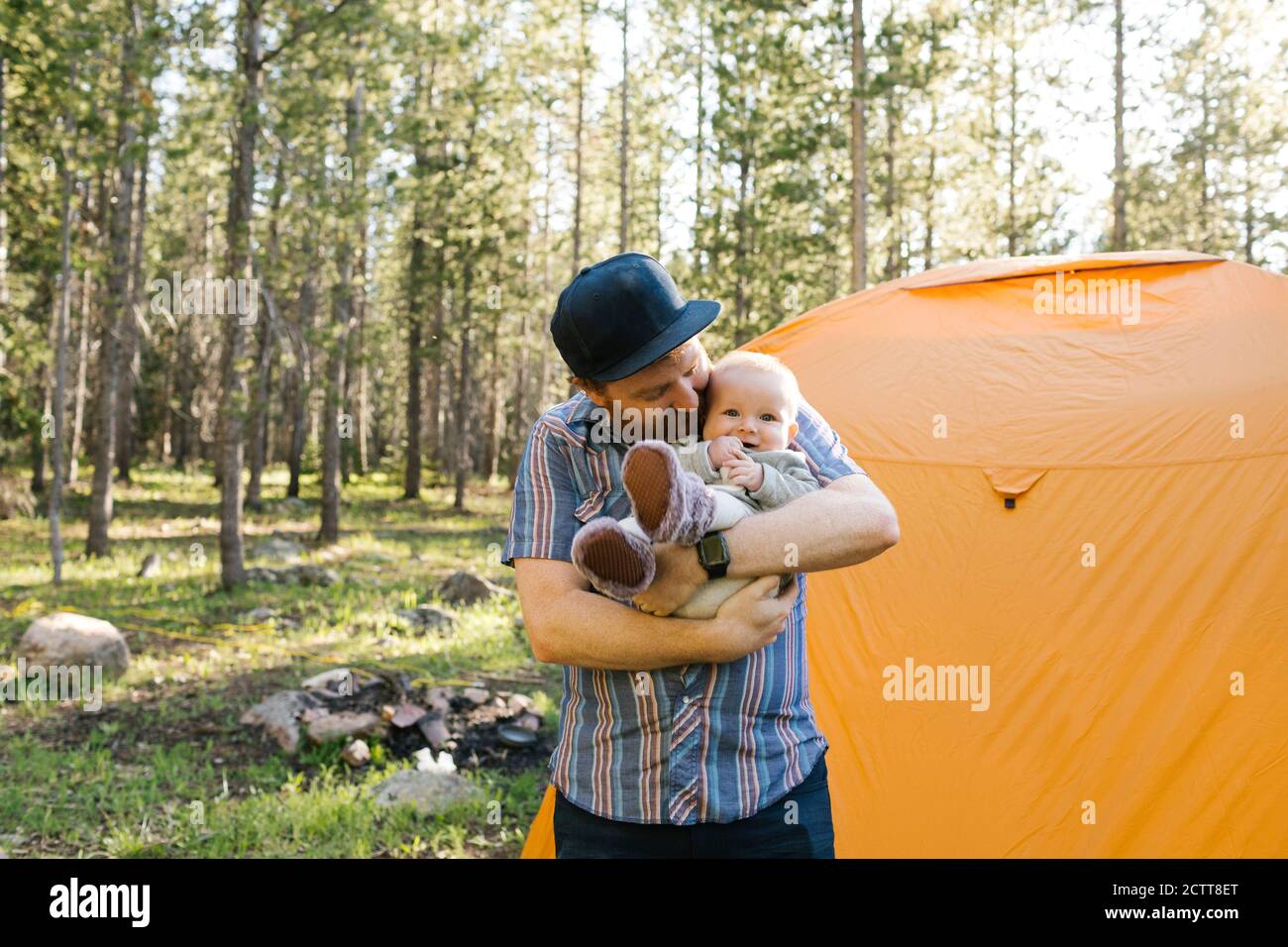 Padre con bambino (6-11 mesi) In piedi da una tenda nella Foresta Nazionale di Uinta-Wasatch-cache Foto Stock
