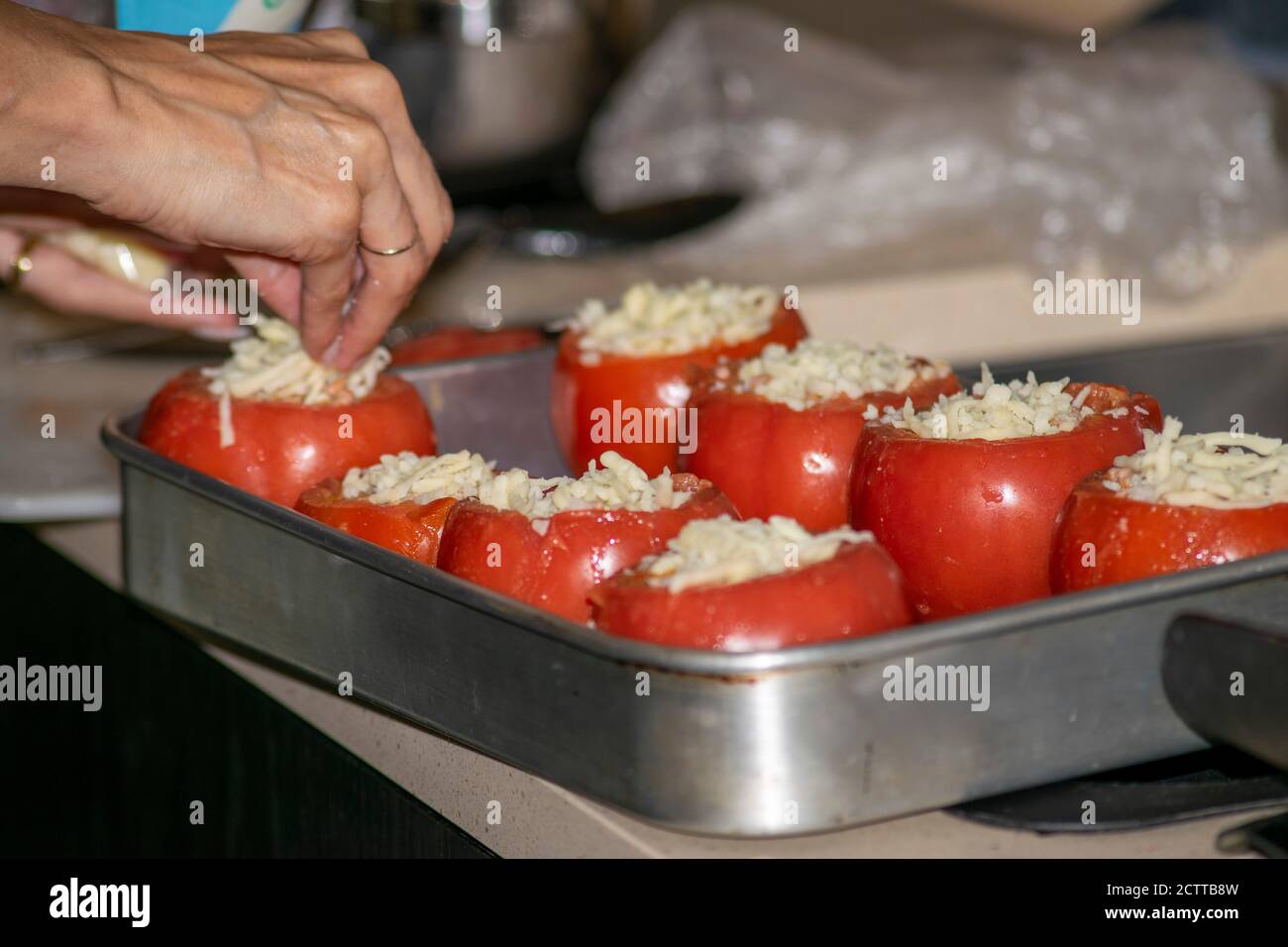 Donne che cucinano pomodori rossi con carne all'interno e formaggio sopra in alto Foto Stock