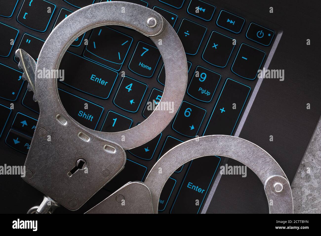 Manette sulla tastiera di un computer portatile, primo piano. Concetto sul tema della punizione per le attività fraudolente nello spazio digitale Foto Stock