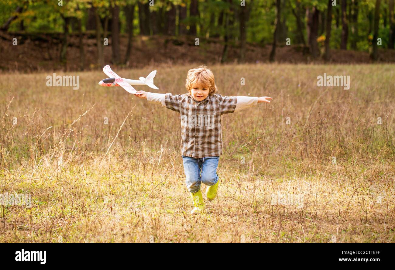 Bambino felice che gioca all'aperto. Happy boy giocare aereo. Ragazzino con aereo. Piccolo capretto sogna di essere un pilota. Bambino che gioca con l'aereo giocattolo Foto Stock