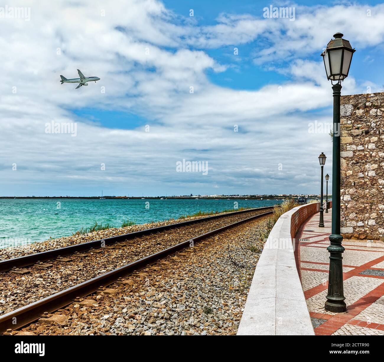 Costa dell'Oceano Atlantico nella città di Faro, Portogallo. Estate giorno di sole. Ferrovia. Aereo che vola sull'oceano. Foto Stock