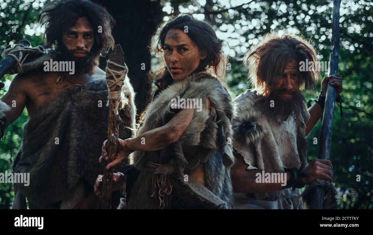 Leader femminile e due Guerrieri Cavemen Primeval minaccia Enemy con la pietra punta Spear, Scream, Defending loro Grotta e territorio nella preistoria Foto Stock