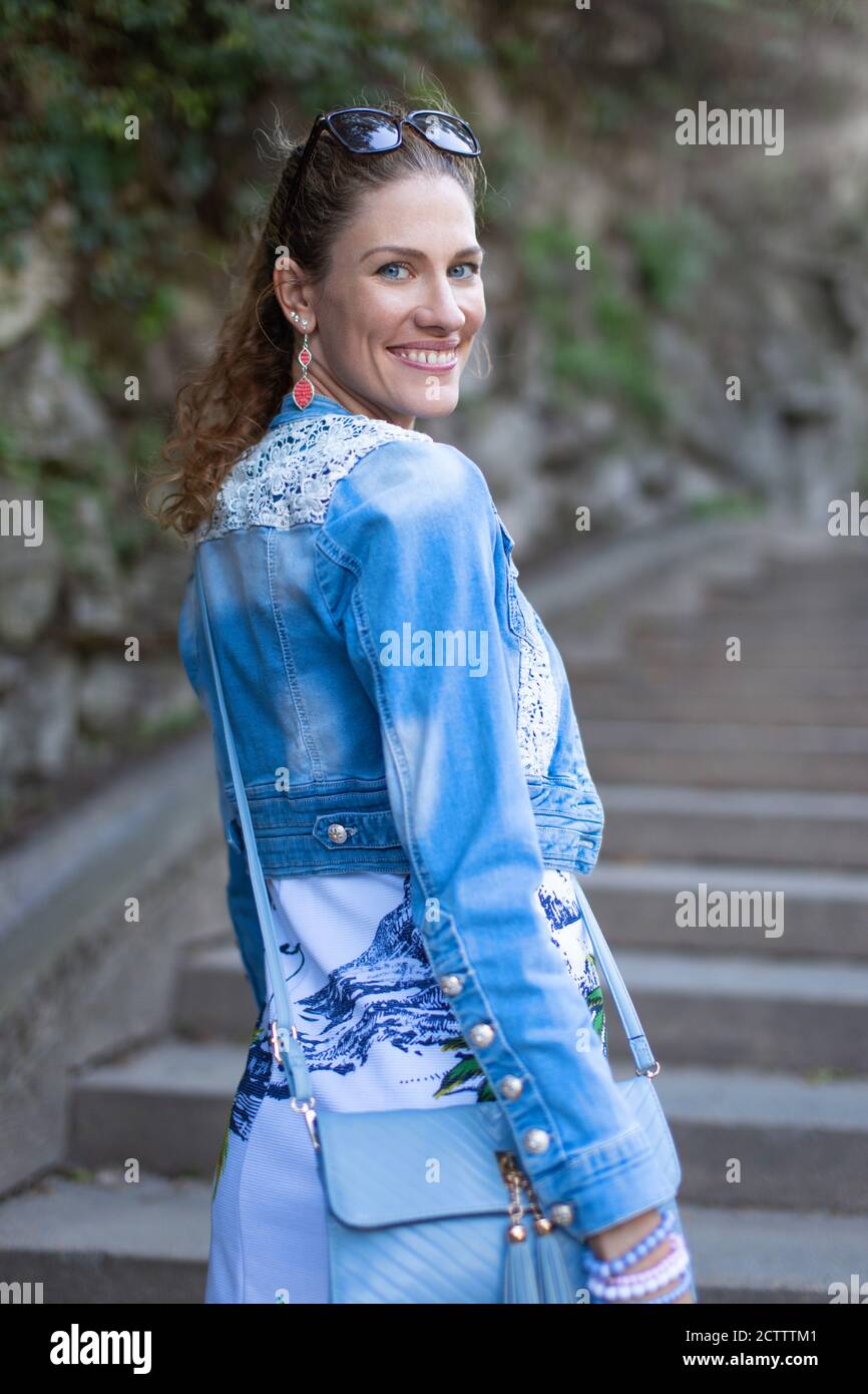 Giovane donna naturale in denim che guarda indietro sulle scale dentro parcheggio Foto Stock