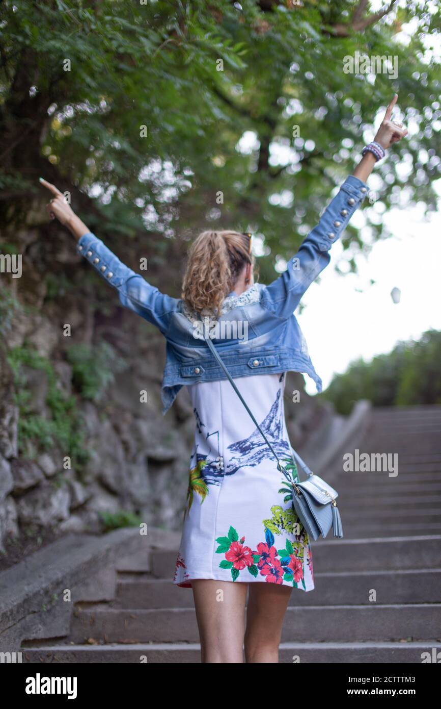 Giovane donna spensierata che salite sulle scale in braccia di parcheggio sollevato Foto Stock