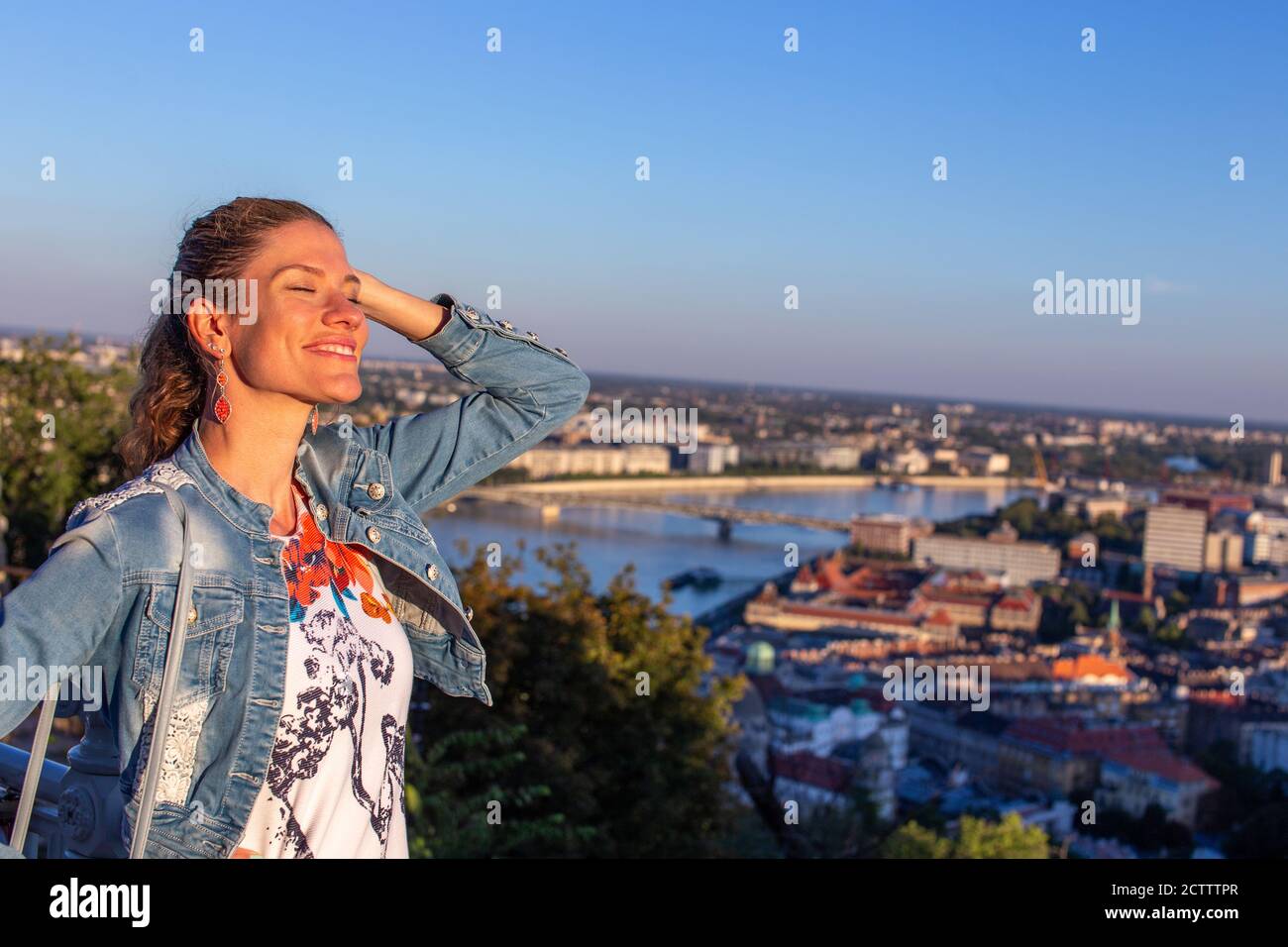 Felice giovane donna urbana che si rilassa al tramonto della città Foto Stock