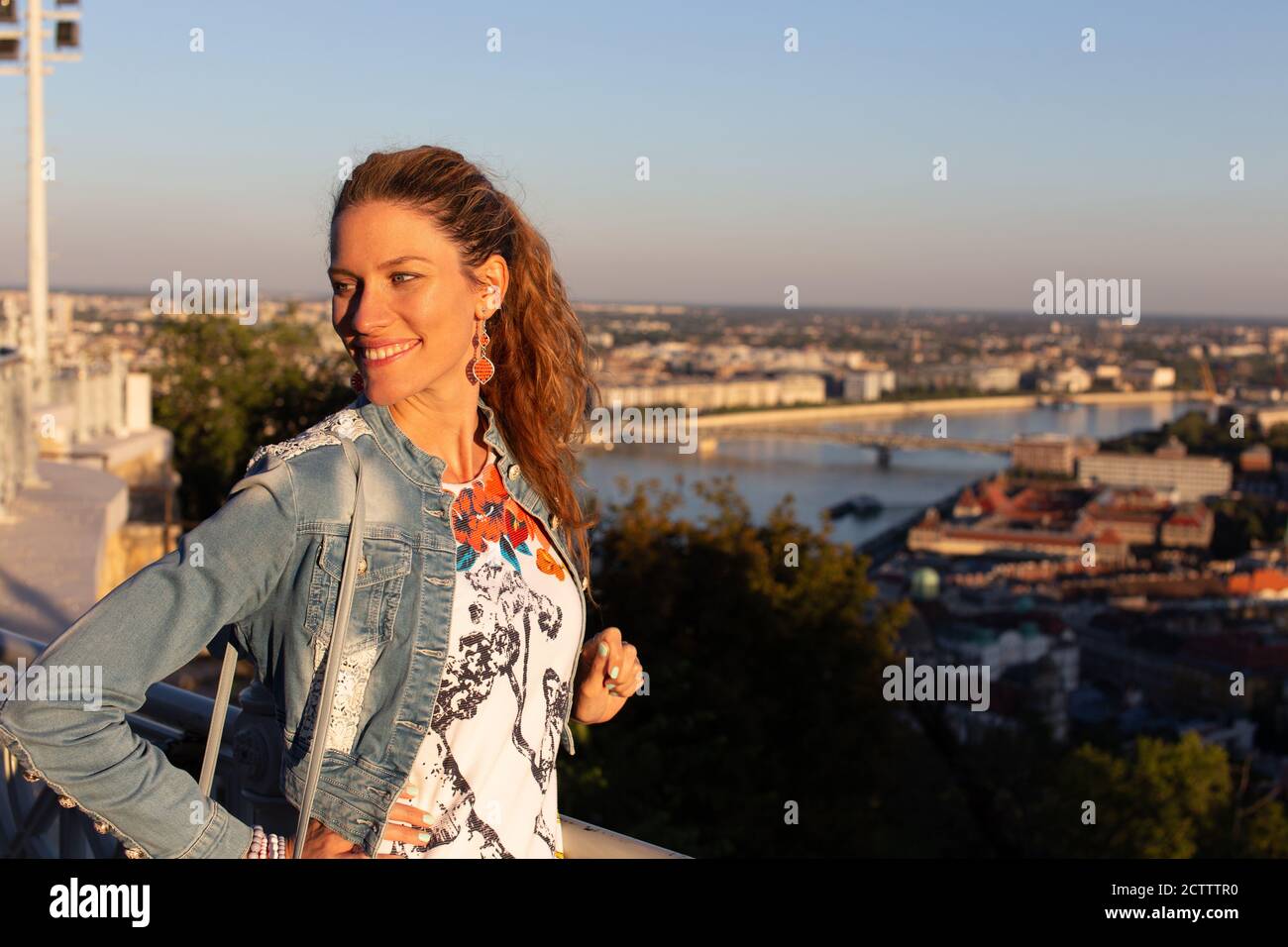 Giovane donna urbana equilibrata che guarda via nel tramonto della città Foto Stock