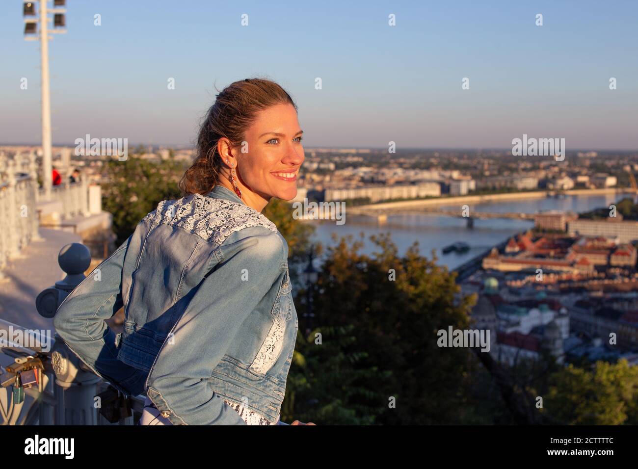 Felice giovane donna urbana che guarda via al tramonto con toothy sorridi Foto Stock