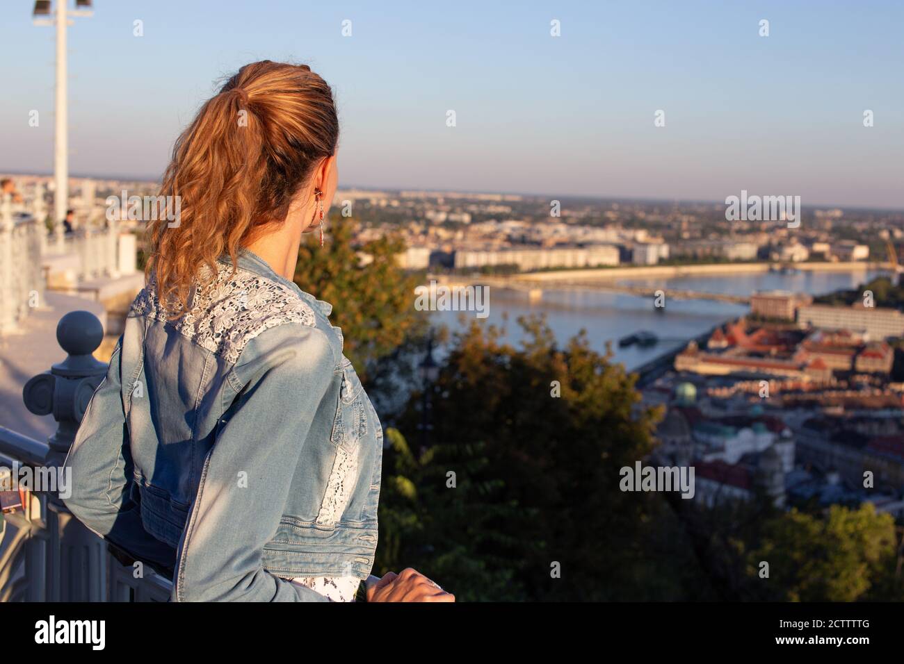 Donna urbana che si chiede nel panorama della città al tramonto Foto Stock