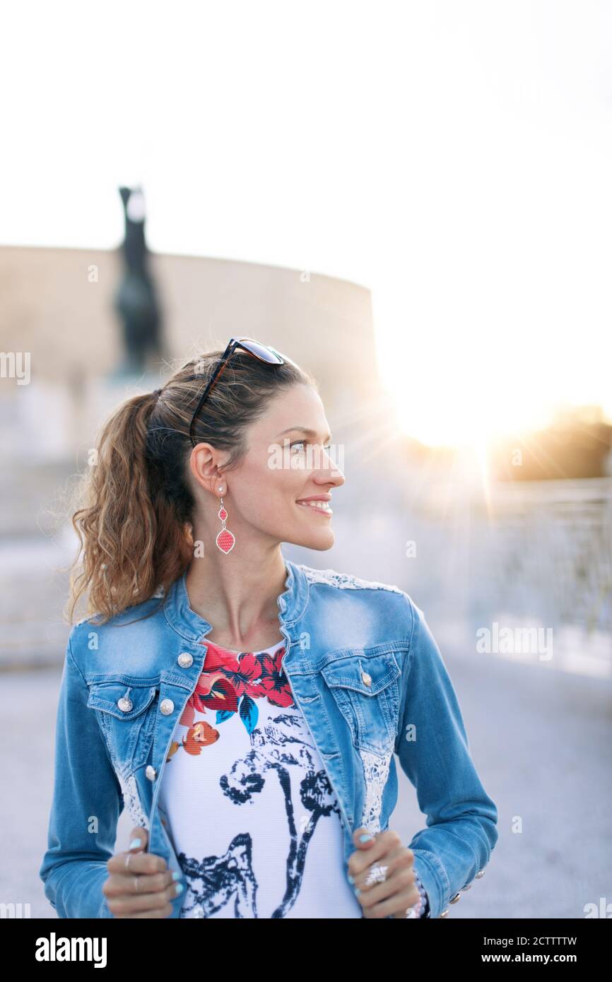 Felice giovane donna urbana che guarda via al famoso tramonto luogo Foto Stock