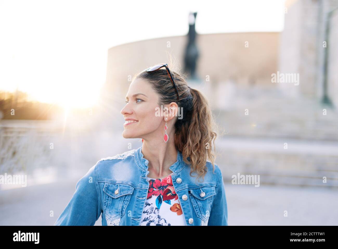 Felice giovane donna che guarda via al famoso posto al tramonto Foto Stock
